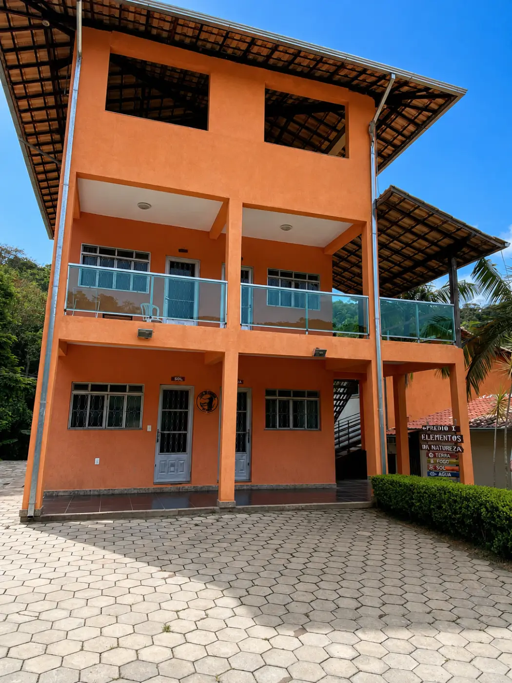 Fachada laranja do Prédio Elementos da Natureza, com as portas das suítes e a placa de madeira